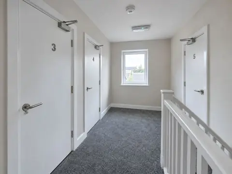 HMO landing with numbered fire doors, overhead door closers and a ceiling smoke detector