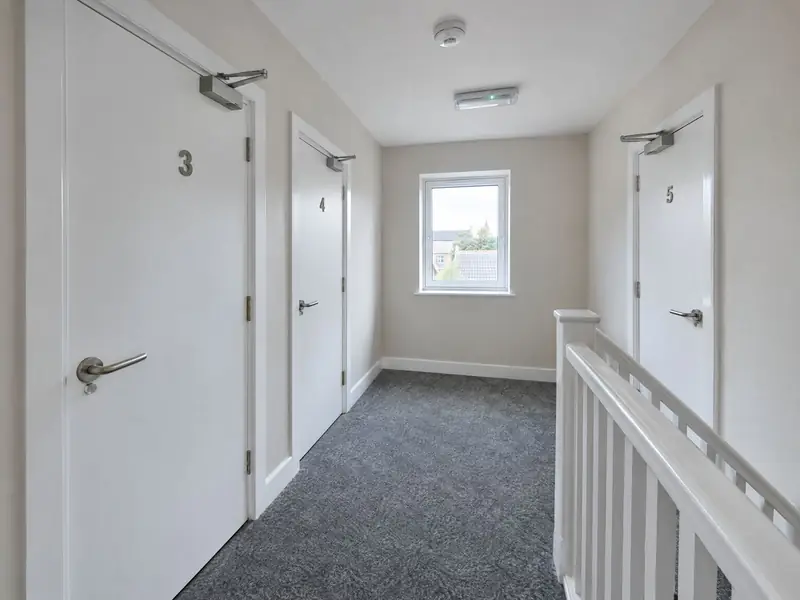 HMO landing with numbered fire doors, overhead door closers and a ceiling smoke detector